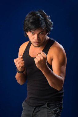Portrait of a young man posing and showing his muscular body. The concept of a healthy lifestyle on blue background.