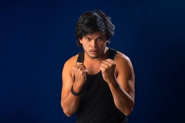 Portrait of a young man posing and showing his muscular body. The concept of a healthy lifestyle on blue background.