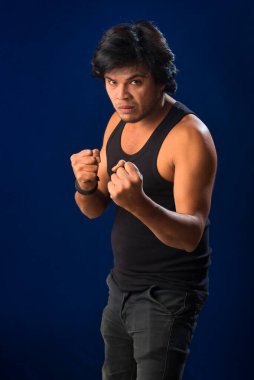 Portrait of a young man posing and showing his muscular body. The concept of a healthy lifestyle on blue background.