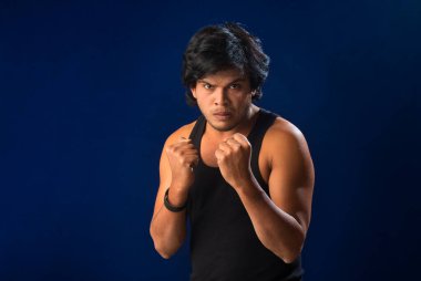 Portrait of a young man posing and showing his muscular body. The concept of a healthy lifestyle on blue background.