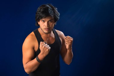 Portrait of a young man posing and showing his muscular body. The concept of a healthy lifestyle on blue background.