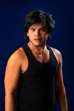 Portrait of a young man posing and showing his muscular body. The concept of a healthy lifestyle on blue background.