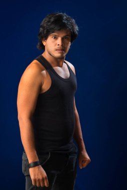 Portrait of a young man posing and showing his muscular body. The concept of a healthy lifestyle on blue background.