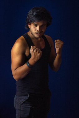 Portrait of a young man posing and showing his muscular body. The concept of a healthy lifestyle on blue background.