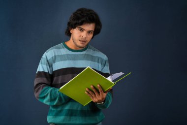 Young happy man holding and posing with the book on background.