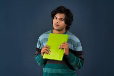 Young happy man holding and posing with the book on background.