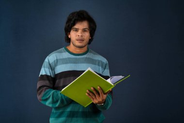 Young happy man holding and posing with the book on background.