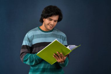 Young happy man holding and posing with the book on background.