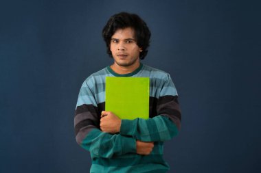 Young happy man holding and posing with the book on background.