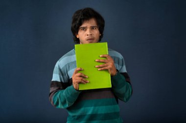 Young happy man holding and posing with the book on background.