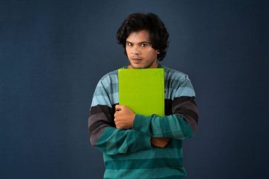 Young happy man holding and posing with the book on background.
