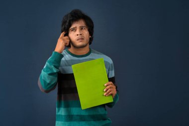 Young happy man holding and posing with the book on background.