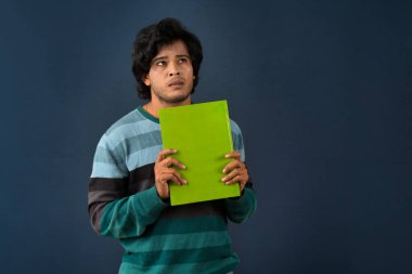 Young happy man holding and posing with the book on background.