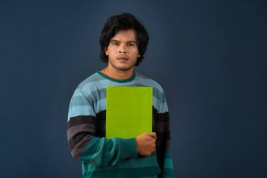 Young happy man holding and posing with the book on background.