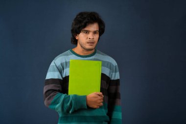Young happy man holding and posing with the book on background.