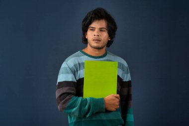 Young happy man holding and posing with the book on background.
