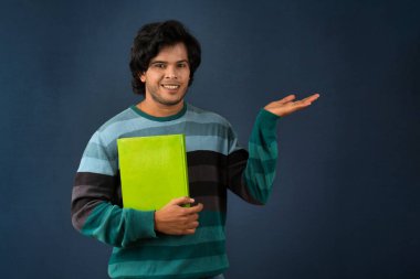Young happy man holding and posing with the book on background.