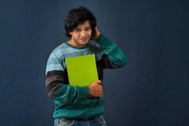 Young happy man holding and posing with the book on background.