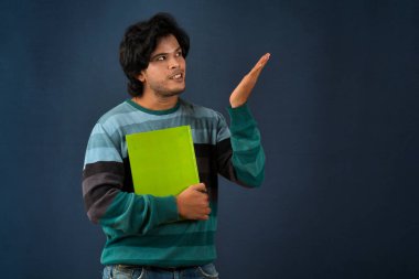 Young happy man holding and posing with the book on background.