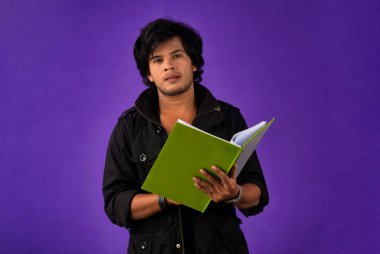 Young happy man holding and posing with the book on background.