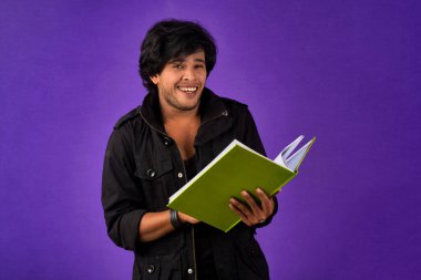 Young happy man holding and posing with the book on background.