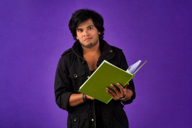 Young happy man holding and posing with the book on background.