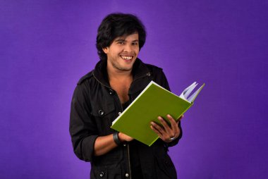 Young happy man holding and posing with the book on background.