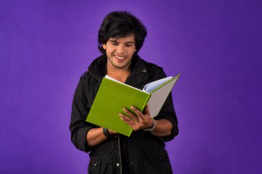 Young happy man holding and posing with the book on background.