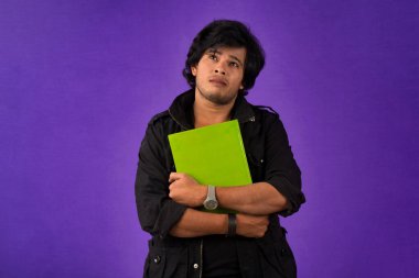 Young happy man holding and posing with the book on background.