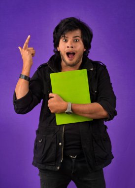 Young happy man holding and posing with the book on background.