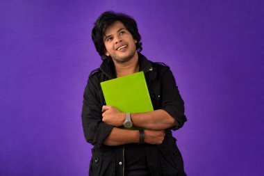 Young happy man holding and posing with the book on background.