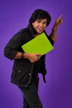 Young happy man holding and posing with the book on background.