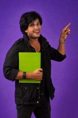Young happy man holding and posing with the book on background.