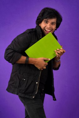 Young happy man holding and posing with the book on background.