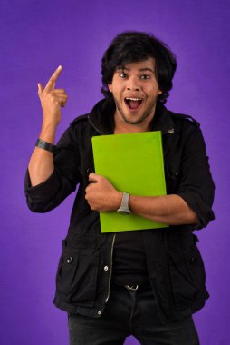 Young happy man holding and posing with the book on background.