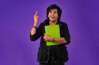Young happy man holding and posing with the book on background.