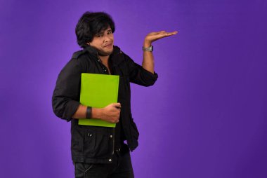 Young happy man holding and posing with the book on background.