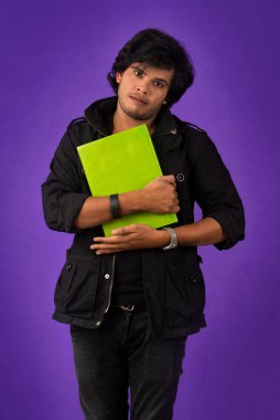 Young happy man holding and posing with the book on background.