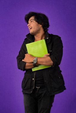 Young happy man holding and posing with the book on background.