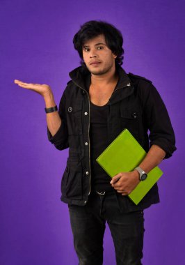 Young happy man holding and posing with the book on background.