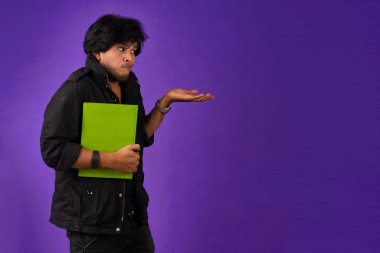 Young happy man holding and posing with the book on background.