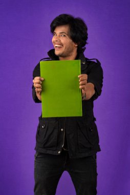 Young happy man holding and posing with the book on background.