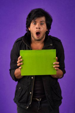 Young happy man holding and posing with the book on background.