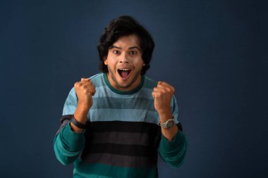 Young handsome man over dark background afraid and shocked with surprise and amazed expression, fear and excited face.