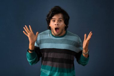 Young handsome man over dark background afraid and shocked with surprise and amazed expression, fear and excited face.