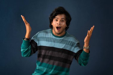 Young handsome man over dark background afraid and shocked with surprise and amazed expression, fear and excited face.