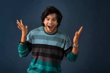 Young handsome man over dark background afraid and shocked with surprise and amazed expression, fear and excited face.