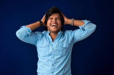 Young handsome man over dark background afraid and shocked with surprise and amazed expression, fear and excited face.
