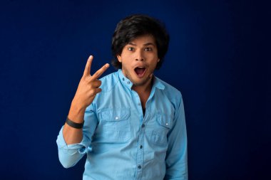 Young handsome man over dark background afraid and shocked with surprise and amazed expression, fear and excited face.