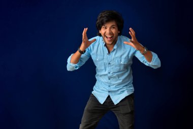 Young handsome man over dark background afraid and shocked with surprise and amazed expression, fear and excited face.